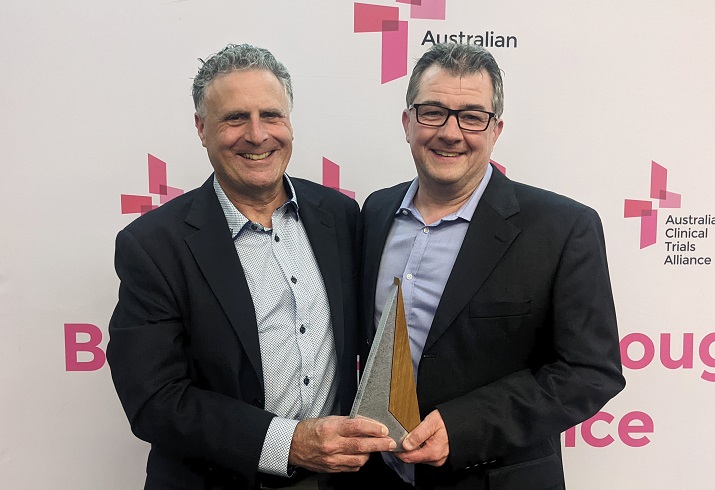 Two people stand together with an award