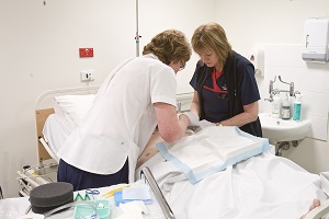 Photograph of 2 staff members treating a patient